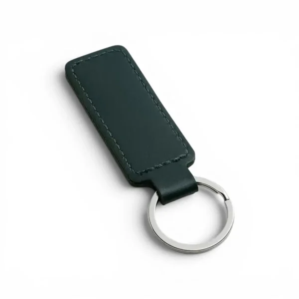 A dark green, blank premium leather keyholder before customisation, showcasing the raw stitching and thick leather grain on a wooden workshop table by WIKXY.